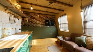 A kitchen with a wooden countertop, a green cabinet, and a brick wall.