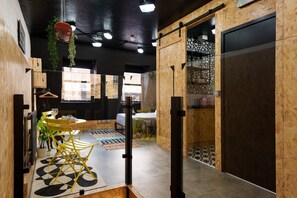 A modern interior with a dining area, wooden walls, and a large window providing natural light.