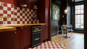 Una cocina con salpicadero de baldosas a cuadros, encimera de madera, lavavajillas negro y una zona de comedor con un tablero de ajedrez.