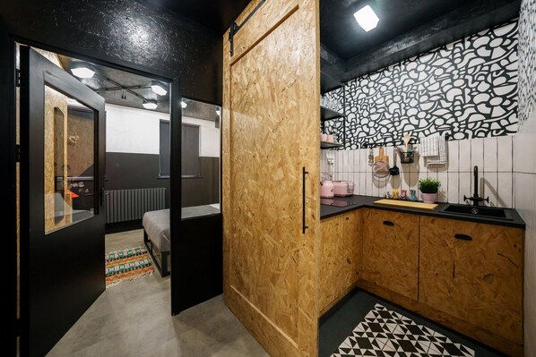 A compact kitchen with wooden cabinets, a black countertop, and a patterned backsplash.