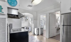 A modern kitchen with a built-in stove, a stainless steel refrigerator, and a clock on the wall.