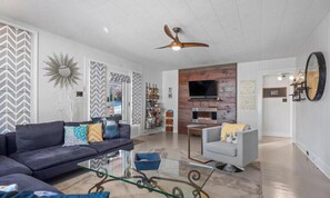 A modern living room with a dark-colored sofa, a glass coffee table, and a fireplace.