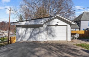 Un garage de plain-pied, avec une façade blanche, un toit en pente et une porte de garage.
