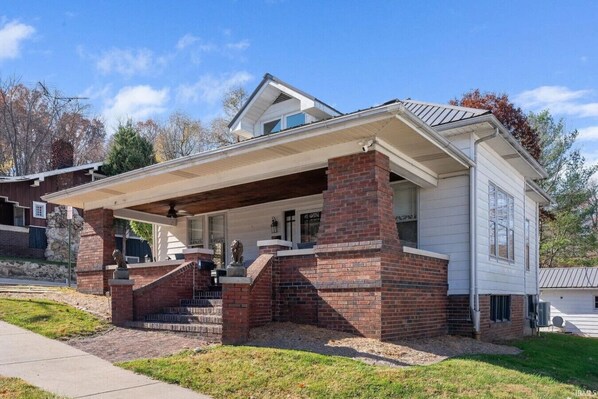 A two-story house with a covered porch and brick foundation.