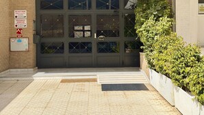 Entrada de edifício com uma grande porta de vidro, uma placa acima com a inscrição 'LA NINA' e uma pequena placa indicando 'NÃO ESTACIONAR' e 'PROIBIDO ESTACIONAR NA ENTRADA'.
