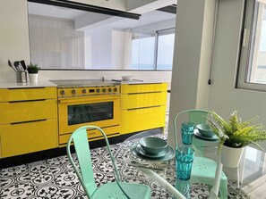 Uma cozinha moderna com fogão amarelo, armários brancos e piso estampado.