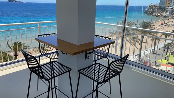 A balcony with a table and chairs overlooking a beach.