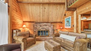 A cozy wooden cabin interior with a fireplace, leather sofas, and a dining area. - Cozy home biking distasnce from the beach by Seaside Vacations & Sales (Chincoteague Island)
