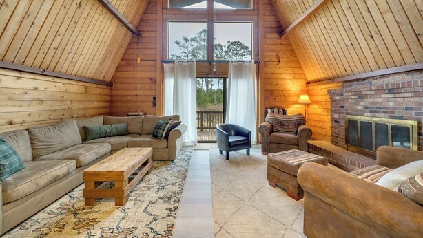 A cozy room with a wooden ceiling, a fireplace, a sofa, a chair, and a rug. - Cozy home biking distasnce from the beach by Seaside Vacations & Sales (Chincoteague Island)