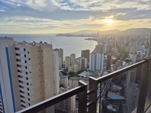 Panorama urbano con grattacieli, una spiaggia e montagne sullo sfondo.