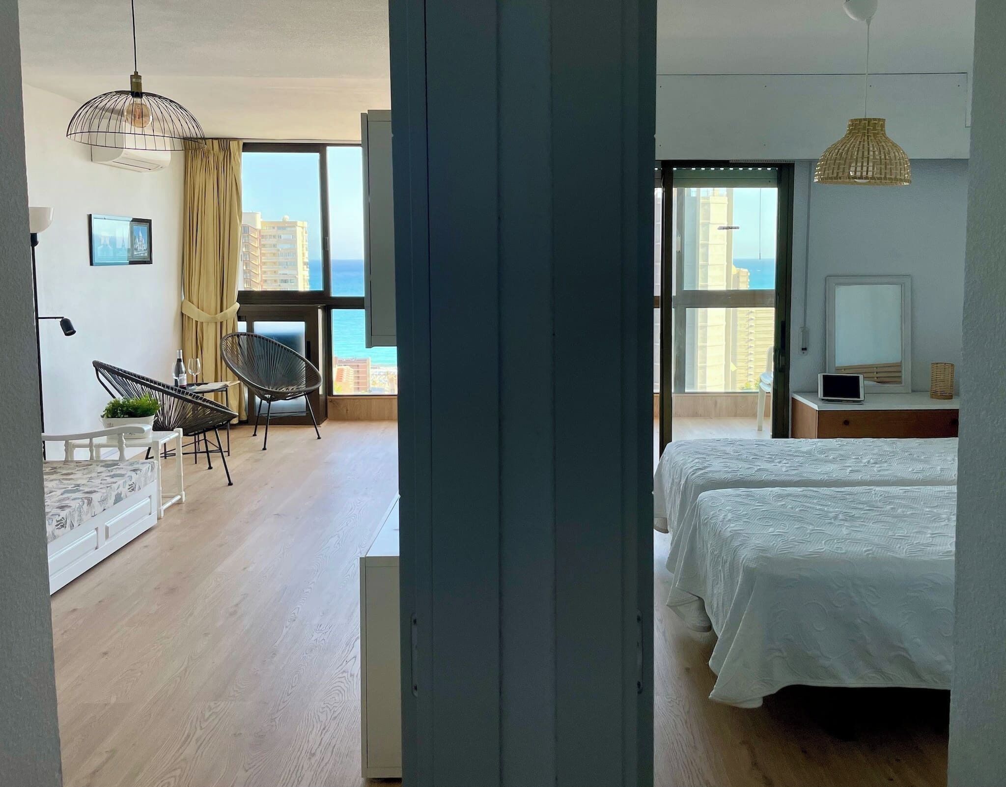 A modern bedroom with a large bed, a TV, and a view of the city.