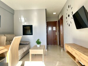 Uma sala de estar moderna com um sofá, uma mesa de centro e uma TV fixada na parede.
