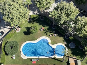 Vista aérea de uma piscina cercada por árvores e grama.