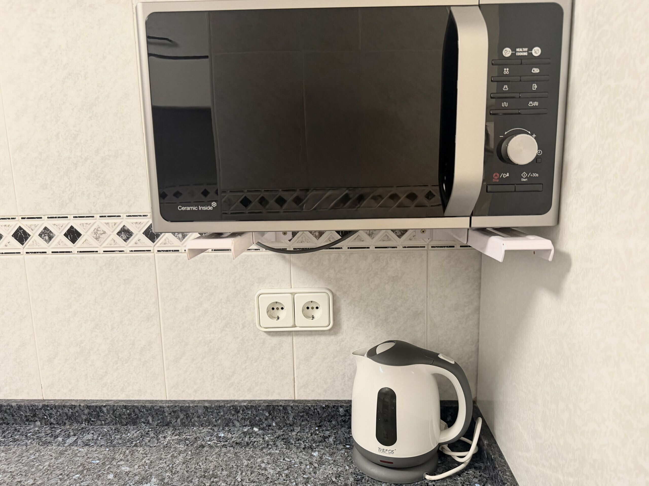 Um forno de microondas com visor digital, painel de controle com vários botões e cabo de alimentação.