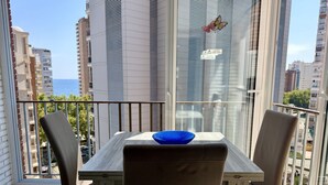 Een balkon met een tafel, stoelen en een blauwe kom.