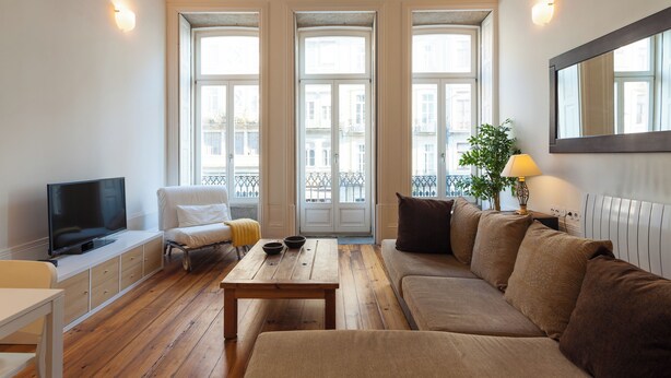 Ein modernes Wohnzimmer mit einer Couch, einem Couchtisch, einem Fernseher und einer Pflanze.