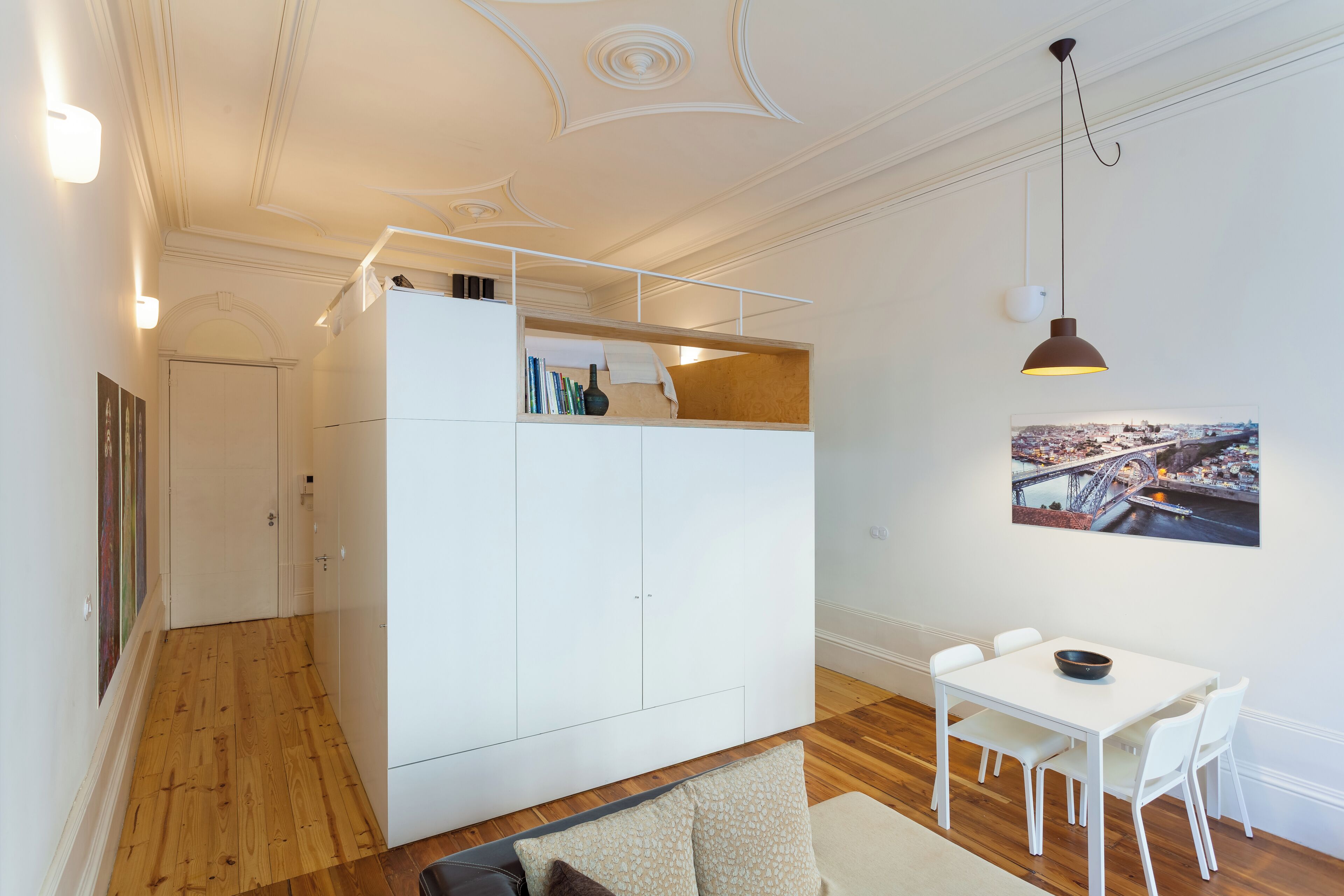A compact living space with a loft bed, a dining area, and a small kitchen.