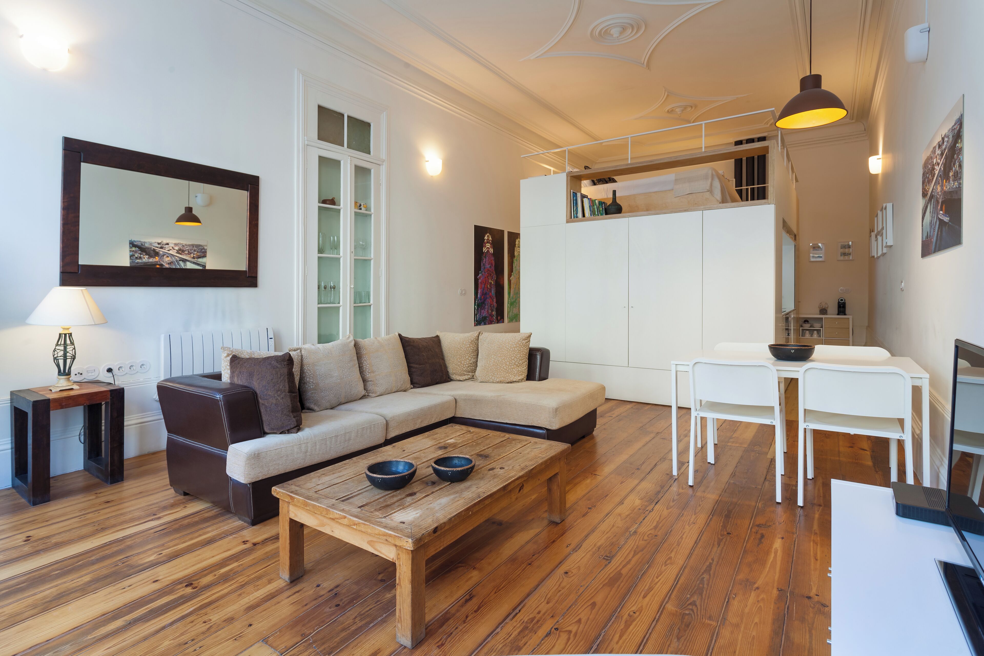 Una sala de estar moderna con un sofá seccional, una mesa de centro de madera, una mesa de comedor con sillas y una zona de cocina arriba.
