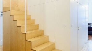 Eine moderne Treppe mit Holzdielen und weißen Wänden, die zu einem Raum mit einem blauen Sofa führt.