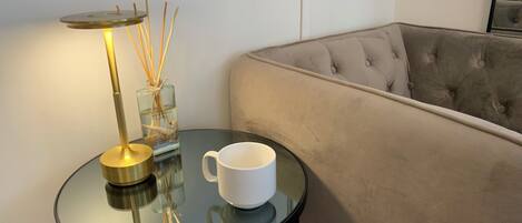 A round glass table with a white mug and a lamp with a glass base.