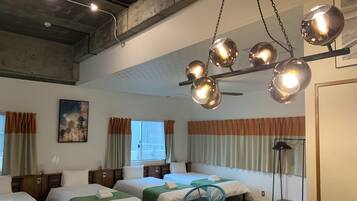 A hotel room with four beds, a ceiling fan, and a large window with curtains.