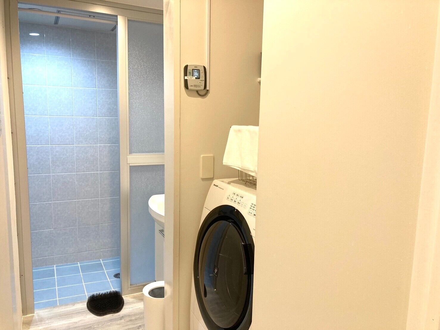 A bathroom with a toilet, a washing machine, and a shower area.