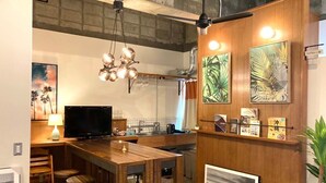 Una cuina moderna amb una illa de fusta, tamboretes de bar, una televisió i obres d'art a les parets.