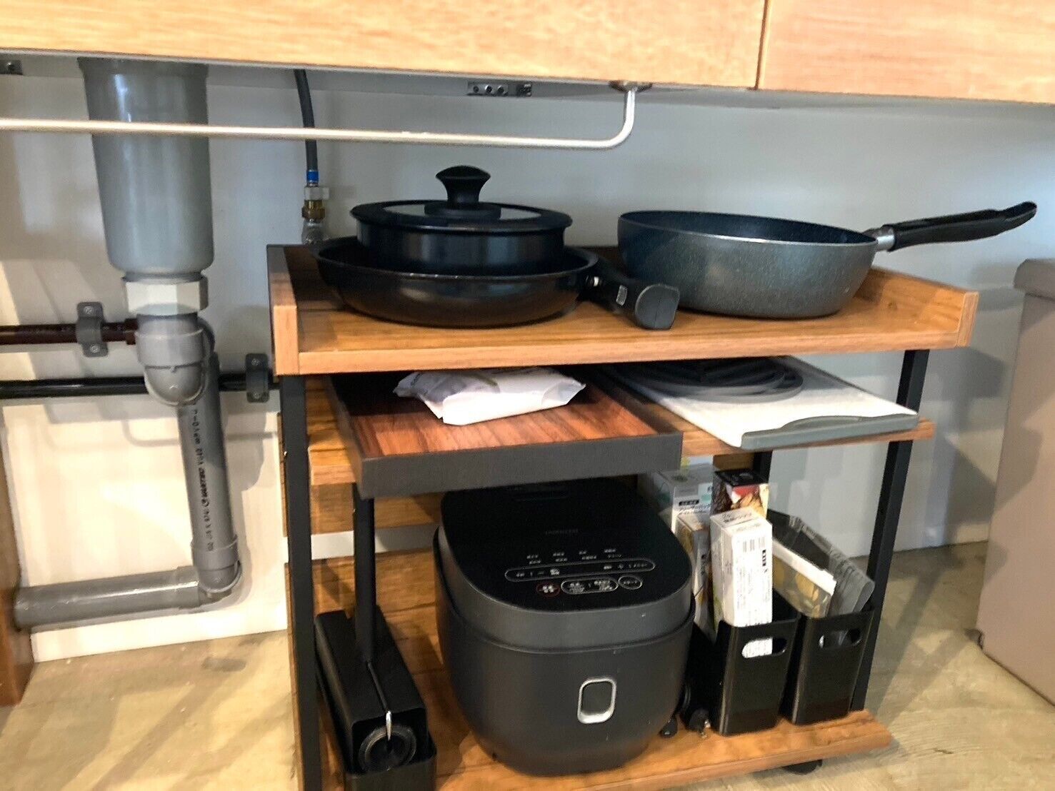 A kitchen with a wooden countertop, a stove, a rice cooker, and a frying pan.
