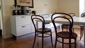 Una cocina moderna con armarios blancos, una cafetera y un cuadro en la pared.