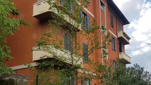 Un edificio de varios pisos con balcones, una entrada vigilada y un cartel de prohibido estacionar.