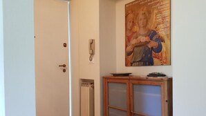 Un pasillo con una puerta blanca, un radiador y un mueble de madera con puertas de vidrio.