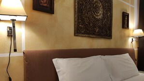 Een hotelkamer met een bruin hoofdeinde, witte beddengoed en een decoratief kunstwerk boven het bed.