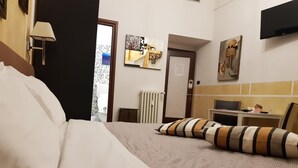 Een hotelkamer met een bed, een bureau, een stoel, een televisie en kunst aan de muren.
