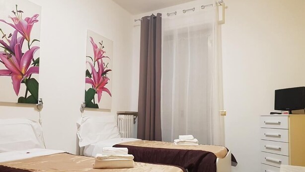 A hotel room with two beds, a TV, and a desk. - Le Campane Apartment Verona Center (VERONA)