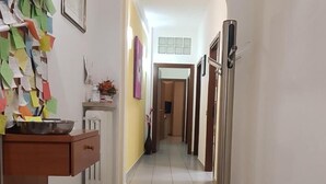 A hallway with a tiled floor, a wooden counter with a bowl, and a wall covered with notes. - Le Campane Apartment Verona Center (VERONA)