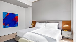 A modern bedroom with a large bed, two bedside tables, and a vibrant abstract painting on the wall.