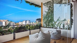 A balcony with a view of the city and the sea.