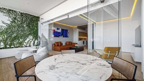 A modern living room with a marble table, a brown leather sofa, and a glass partition.