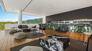 Un espace de détente extérieur moderne, doté d’un bar, de sièges et offrant une vue sur les collines.