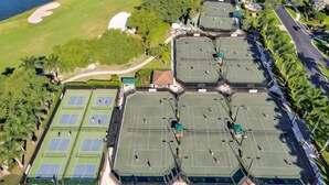Vue aérienne d’un complexe sportif comprenant plusieurs courts de tennis, un parcours de golf et de nombreux espaces verts.