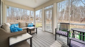 A covered porch with a sofa, chairs, and a table.