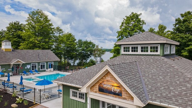 A building with a pool, a sign reading "The Water's Edge," and a view of a lake.