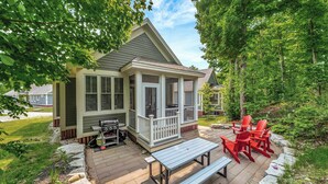 A house with a covered porch, a barbecue grill, and outdoor seating.