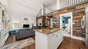 Una cocina moderna con una pared decorativa de madera, una isla integrada y un refrigerador de acero inoxidable.