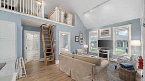 Un vaste espace de vie avec une chambre en mezzanine, un plancher en bois et une grande fenêtre.