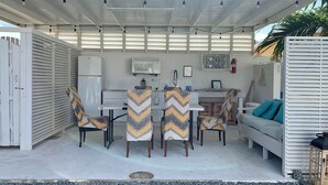 Ein überdachter Essbereich im Freien mit Tisch, Stühlen und einer Couch.