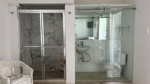 Ein Badezimmer mit Duschkabine aus Glas, einem weißen Waschbecken und einer Toilette.