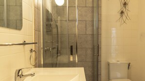 A bathroom with a glass-enclosed shower, a white sink, and a toilet. - Renovated Provencal studio, in the heart of the village of Eyragues, beautiful flower-filled courtyard (Eyragues)