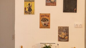 A dining table with a vintage toaster and a small vase of flowers, flanked by two wooden chairs. - Renovated Provencal studio, in the heart of the village of Eyragues, beautiful flower-filled courtyard (Eyragues)