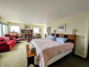 Ein Schlafzimmer mit einem großen Bett, einem roten Sofa, einer Holzkommode und einem Kamin.